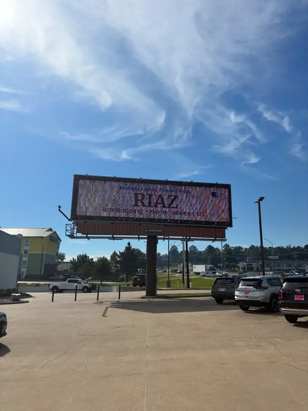 A RIAZ digital billboard over a Tyler parking lot against a blue sky