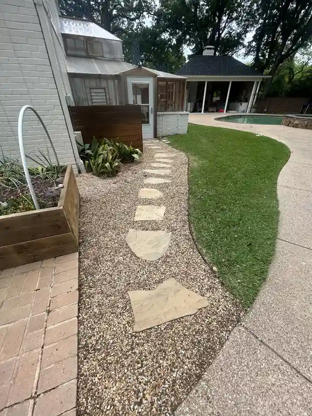 Flagstone stepping path set in pea gravel beside a lawn edge, with a cedar planter and a pool beyond